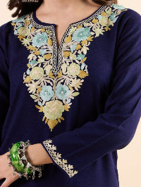 Woman wearing a navy blue embroidered top on a beige background